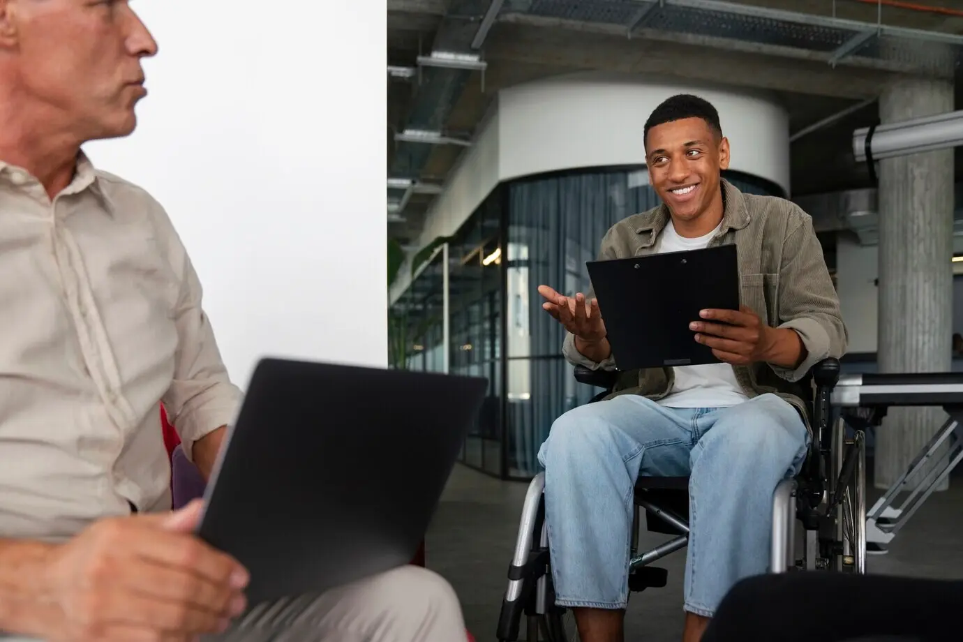 Мужчина с инвалидностью в инвалидной коляске, работающий в офисе.